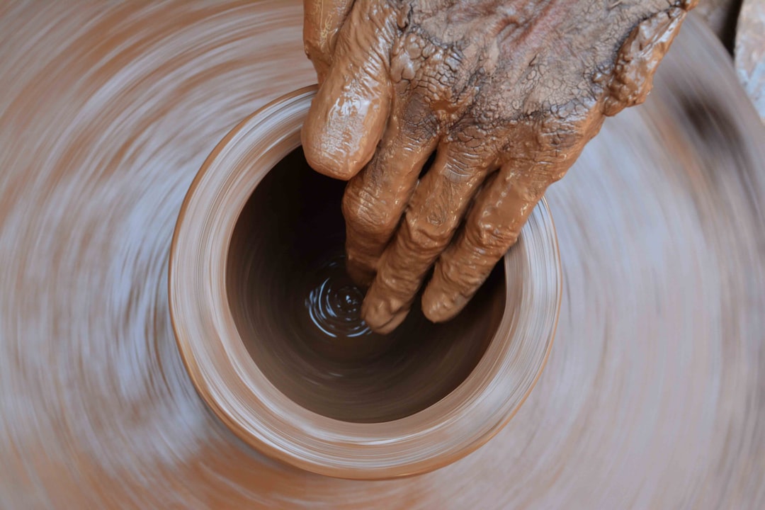 Closeup of hands shaping the inside space of a clay pot on a spinning pottery wheel