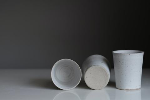 Three ceramic bowls of speckled stoneware, one upright and two on their sides.